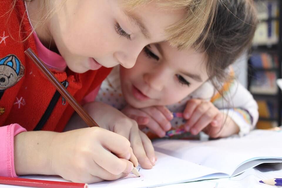 young girl showing a younger boy how to draw